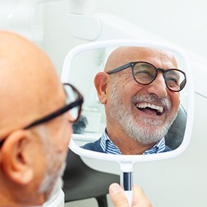 Man with black glasses smiling in reflection in mirror
