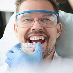 A man receiving a transparent plastic mouthguard from his dentist