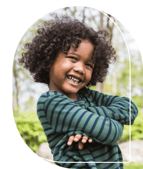 Smiling child crossing their arms outdoors after seeing childrens dentist in Wallingford