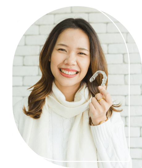 Woman grinning while holding Sure Smile clear aligners in Wallingford