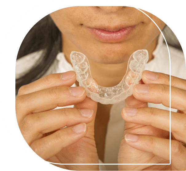 Woman holding a clear aligner near her mouth