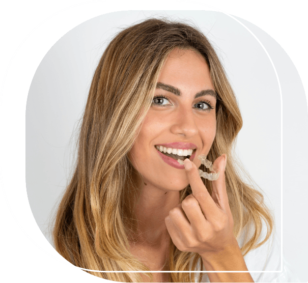 Smiling woman about to place a clear aligner over her teeth