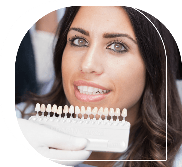 Woman smiling while dentist holds row of veneers next to her teeth