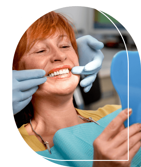 Woman in dental chair looking at her smile in a mirror with dental implants in Wallingford