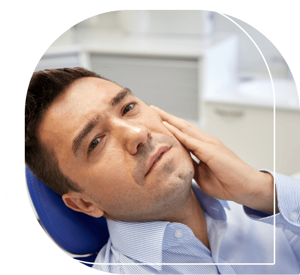 Man holding his jaw in pain while laying in dental chair