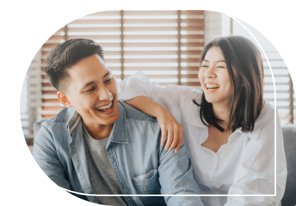 Young man and woman laughing together while sitting on couch