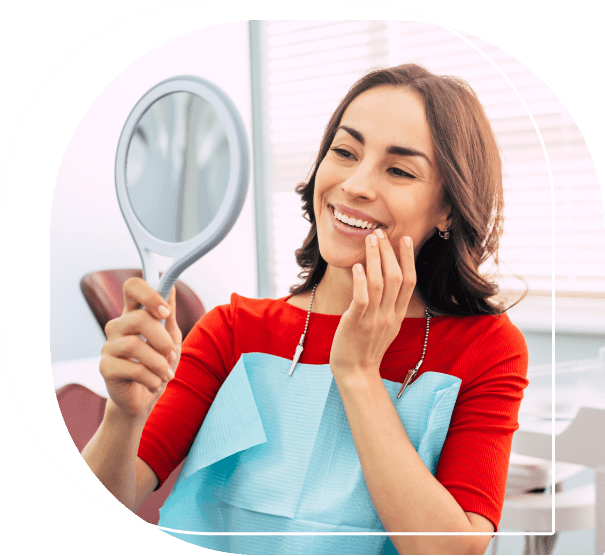 Woman in dental chair holding a mirror and admiring her smile