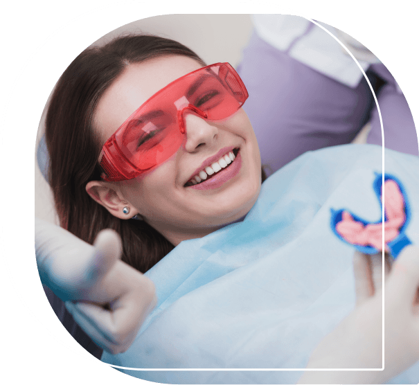 Young woman in dental chair having fluoride applied to her teeth