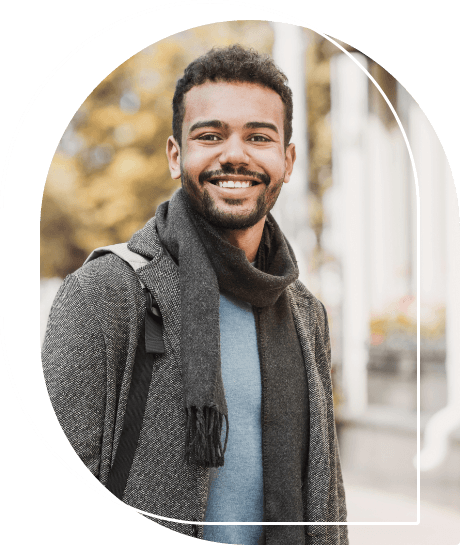 Young man in coat and scarf smiling outdoors